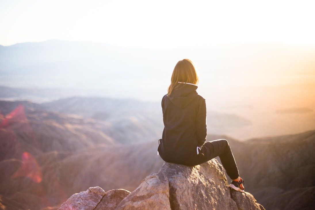 Woman Sitting on a Cliff at Sunset